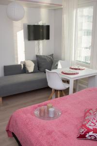 Lahti City Home في لاهتي: غرفة معيشة مع أريكة وطاولة مع سجادة وردية