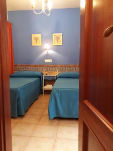 a room with two beds and a blue wall at Pension Doña Trinidad in Seville
