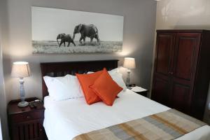 a bedroom with a bed with two elephants painting on the wall at Hummingbird's Nest in Nelspruit