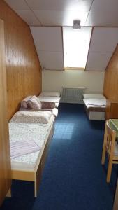 a room with three beds and a window at Penzion Tendr in Deštné v Orlických horách