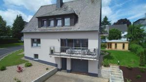 Cette maison blanche dispose d'un balcon avec des chaises. dans l'établissement Gästehaus Eifelzauber, à Kelberg