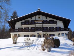 a large white building with a roof in the snow at Bergschlössl Fewo 28 in Oberaudorf