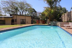 a swimming pool with blue water in a yard at Hummingbird's Nest in Nelspruit