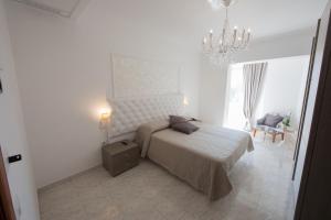 Habitación blanca con cama y lámpara de araña. en Hotel Imperiale, en Terzigno