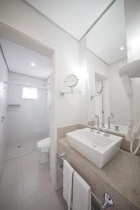 a white bathroom with a sink and a shower at The Falls Hotel in Guarujá