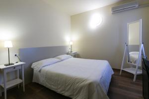 a bedroom with a white bed and a mirror at Albergo Il Cochino in Montale