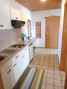 a kitchen with white cabinets and a tile floor at Am Waldeck 10 App. 1002 in Freudensee