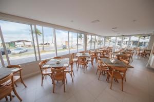 a restaurant with wooden tables and chairs and windows at The Falls Hotel - Frente mar in Guarujá