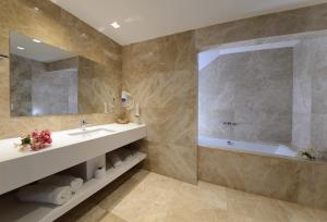 a bathroom with a sink and a tub and a mirror at Lugga Boutique Hotel & Beach in Ortakent