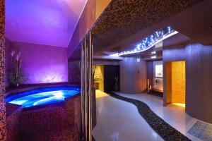 bañera de hidromasaje en una habitación con iluminación púrpura en Gloria Business Hotel, en Blagovéshchensk
