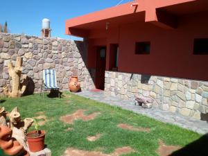 une maison avec un mur en pierre et une chaise dans une cour dans l'établissement El Cardon Hospedaje, à Huacalera