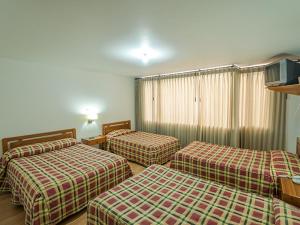 a hotel room with three beds in a room at Hotel Tuvalu in Paipa