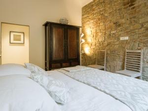 フィレンツェにあるMamo Florence - San Firenze Luxury Apartmentの石壁のベッドルーム1室(白いベッド1台付)