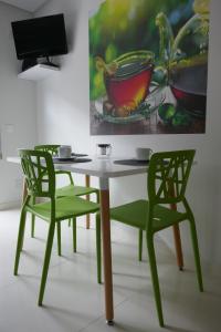 a table with two green chairs and a painting at Two Churches Apartment in Leiria