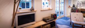 a living room with a flat screen tv and a chair at Joans B&B in Zaandam