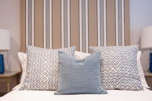 a bed with blue and white pillows on it at Suites at number Ten in Broadstairs