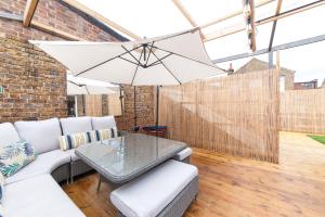 a patio with a white couch and an umbrella at Suites at number Ten in Broadstairs