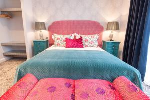 a bedroom with a large bed with pink pillows at Suites at number Ten in Broadstairs