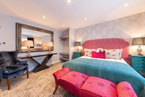 a bedroom with a bed and a chair and a mirror at Suites at number Ten in Broadstairs