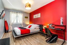 a bedroom with a red wall with a bed and a desk at Logis Hôtel Restaurant Résidence in Nissan-lez-Enserune