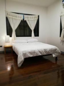 een slaapkamer met een wit bed en een raam bij Comeneetee Uthai in Ban Khok Mo