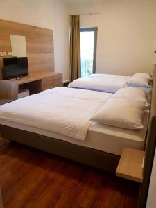 a bedroom with two beds and a desk with a television at Bara Bay in Metajna