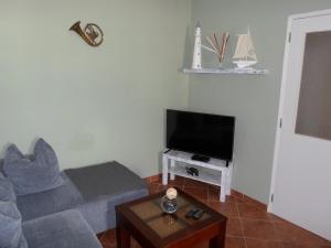 a living room with a couch and a flat screen tv at Casa das Portas in Faro