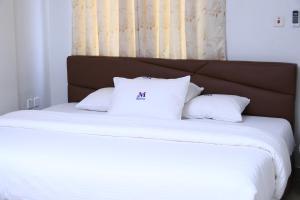 Una cama con dos almohadas blancas encima. en Mawuli Hotel, en Obuassi