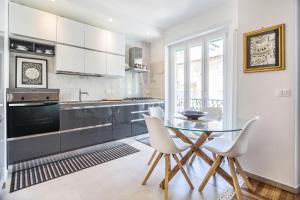 cocina con mesa de cristal y sillas blancas en Luxury Central Apartment, en Turín