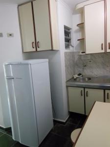 a kitchen with a white refrigerator and a sink at Praia Sul Studios in Peruíbe