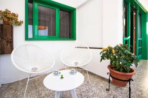 2 weiße Stühle, ein Tisch und eine Pflanze in der Unterkunft Casa Lanza in Playa Honda