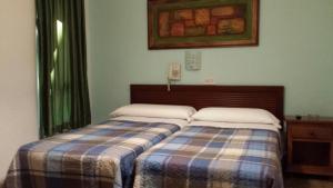 1 dormitorio con 2 camas y teléfono en la pared en Hostal Ronda, en Córdoba