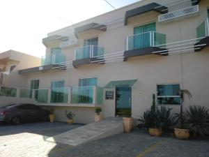 a building with balconies and a car parked in a parking lot at Praia Sul Studios in Peruíbe