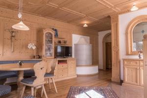 cocina con mesa y sillas y TV en Apartments Ciastel, en San Vigilio Di Marebbe
