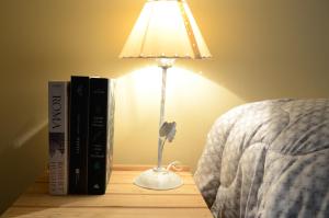 una lámpara en una mesa junto a una cama con libros en B3 Apartments en Formosa