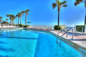 een zwembad met palmbomen en de oceaan bij Bahama House - Daytona Beach Shores in Daytona Beach