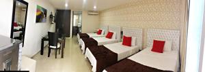 a row of beds in a room with red pillows at Hotel Boutique El Poblado in Neiva
