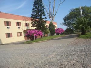 an empty street with a building and pink flowers at Trevo Parque Hotel in São Sepé