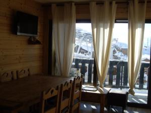 una sala da pranzo con tavolo e una grande finestra di Chalet Amandine a LʼAlpe-dʼHuez