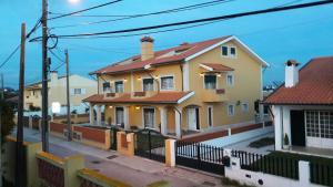 a yellow house with a red roof on a street at A Casa da Ti Laura - AL in Aveiro