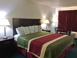 een hotelkamer met een groot bed en twee lampen bij Travel Inn & Suites Atlanta Texas in Atlanta