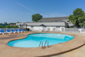 a large swimming pool with blue chairs and a building at Days Inn by Wyndham Columbus East Airport in Columbus