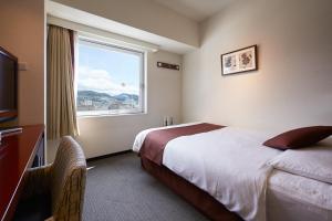 a hotel room with a bed and a window at S Peria Hotel Nagasaki in Nagasaki