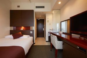 長崎市にあるエスペリアホテル長崎のベッドとデスクが備わるホテルルームです。