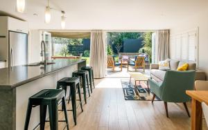 a kitchen and living room with a counter and stools at Island Time in Oneroa