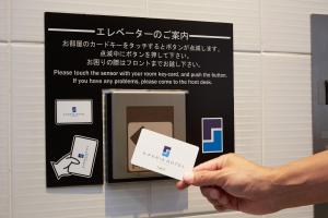 a person holding a piece of paper in front of a sign at S Peria Hotel Nagasaki in Nagasaki