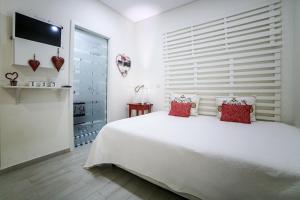 a white bedroom with a large white bed with red pillows at Estúdio 40A in Nazaré
