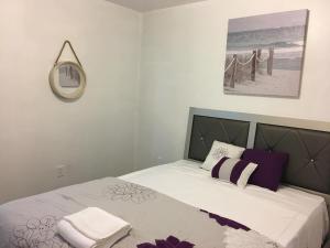 una camera da letto con un letto con lenzuola bianche e cuscini viola di Mojoy Homesuites At Runyon a Newark