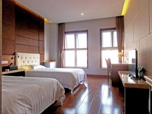 a hotel room with two beds and a desk at Qingdao Hua Qi Kaiserdom Hotel in Qingdao