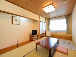 
a living room with a table, chairs and a tv at Hotel Wellness Notoji in Hakui
